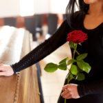 trumna, kobieta ubrana na czarno z czerwona różą